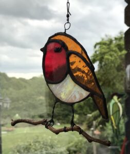 A garden Robin sitting on a natural twisted branch with a wire hanger,